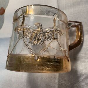 Antique pressed glass cup featuring a raised eagle and drum motif.